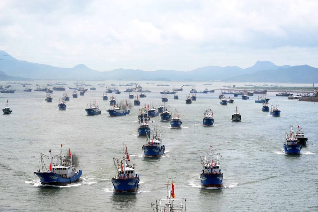 A fishing fleet departs from a harbor after the summer fishing moratorium.