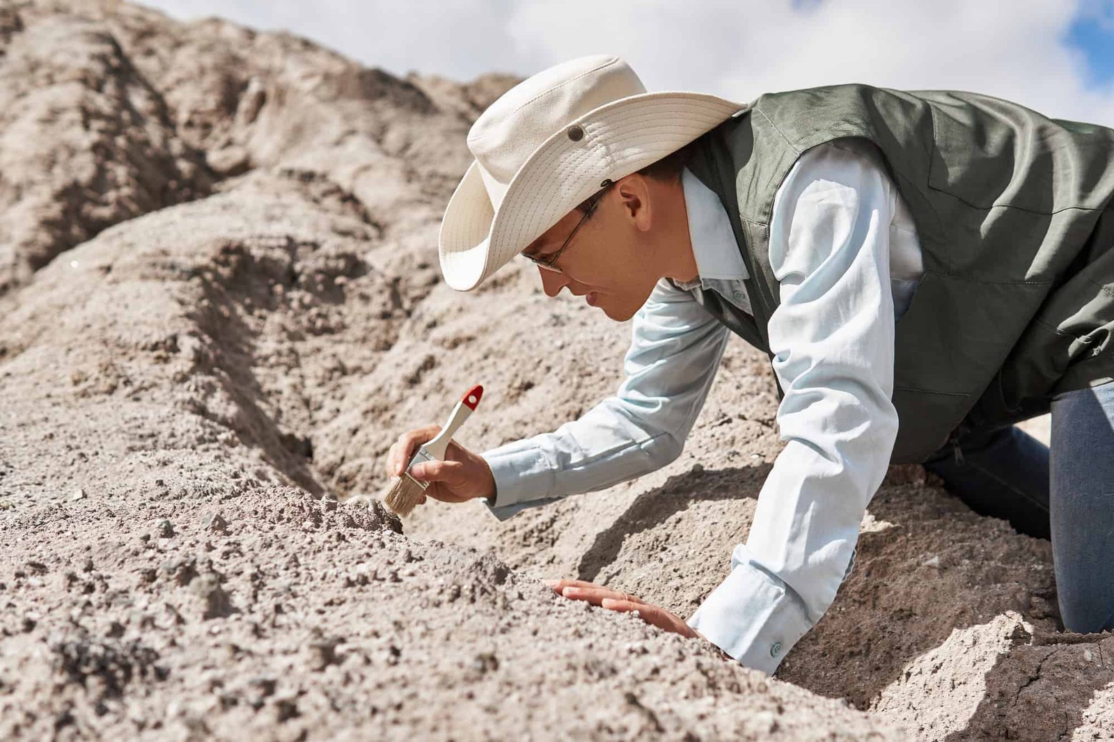 Paleontologist or cleans the find with a brush in the desert.