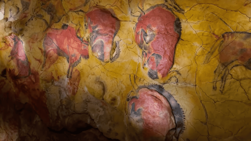 Cave wall covered in red paintings.