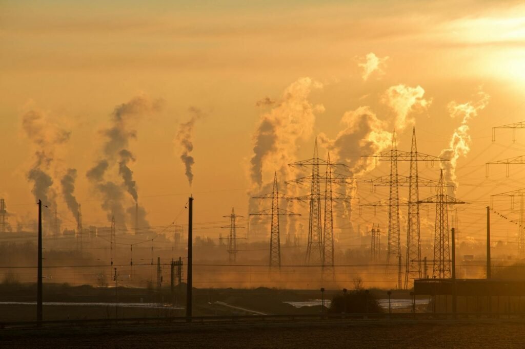 Silhouette of power lines and industrial smoke at sunset.