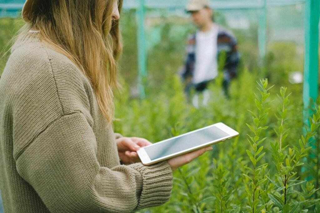 Woman taking down notes in a greenhouse for managing plant growth.