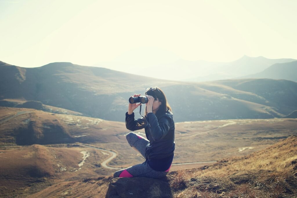 Woman using binoculars to look from afar.