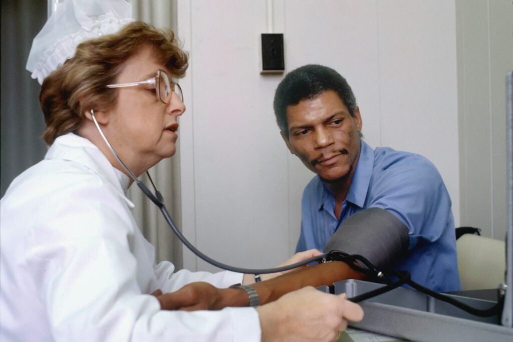 An elderly African American man getting his blood pressure checked by a nurse.