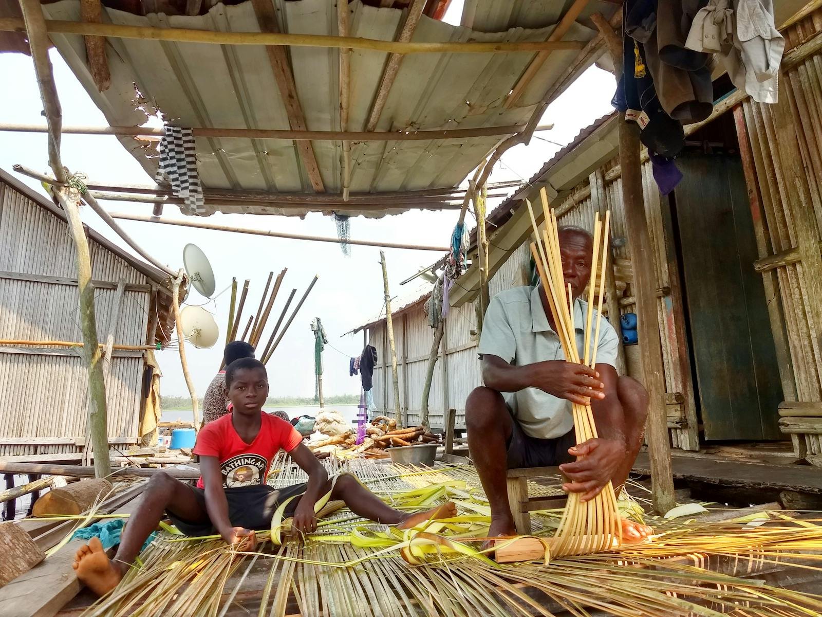 An artisan and a child engaged in traditional weaving techniques outdoors.