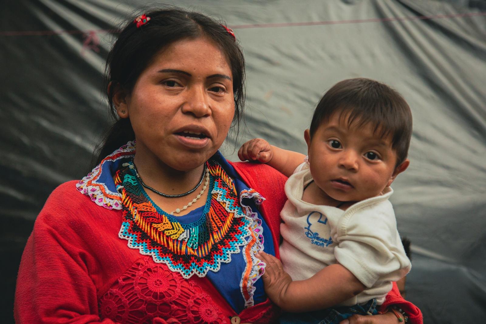 A mother lovingly holds her baby in a vibrant traditional dress showcasing Colombian culture.