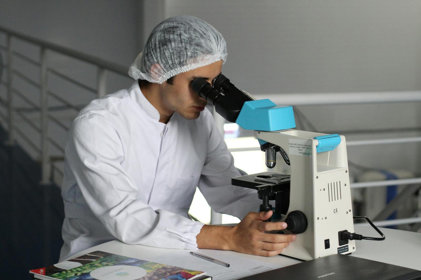 Scientist in a lab coat using a microscope to conduct research.