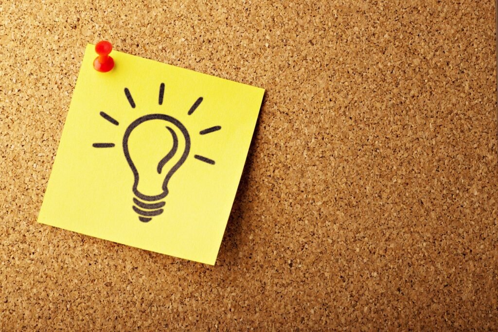 Sticky note with lightbulb symbol pinned on corkboard