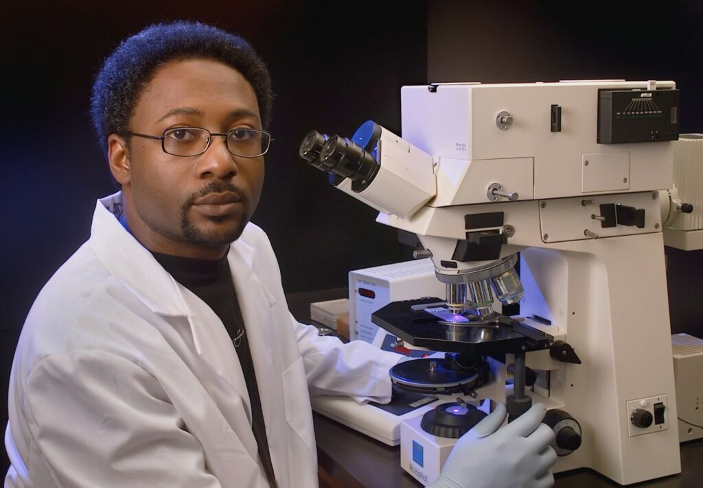 Microbiologist next to a microscope.