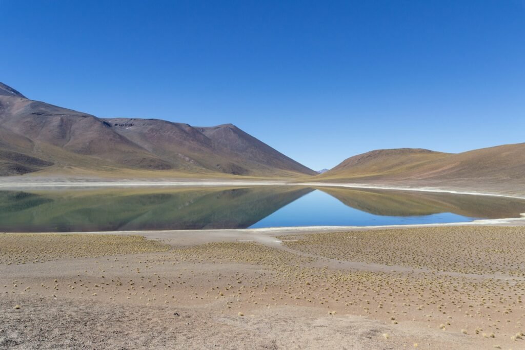 A serene mountain lake reflecting a clear blue sky.