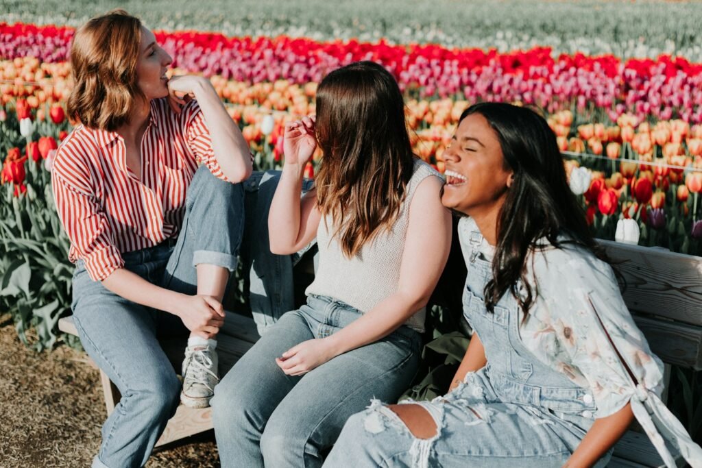 Women sitting wooden bench by the tulip flower field.