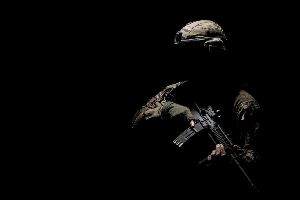 Soldier holding a rifle in the dark.