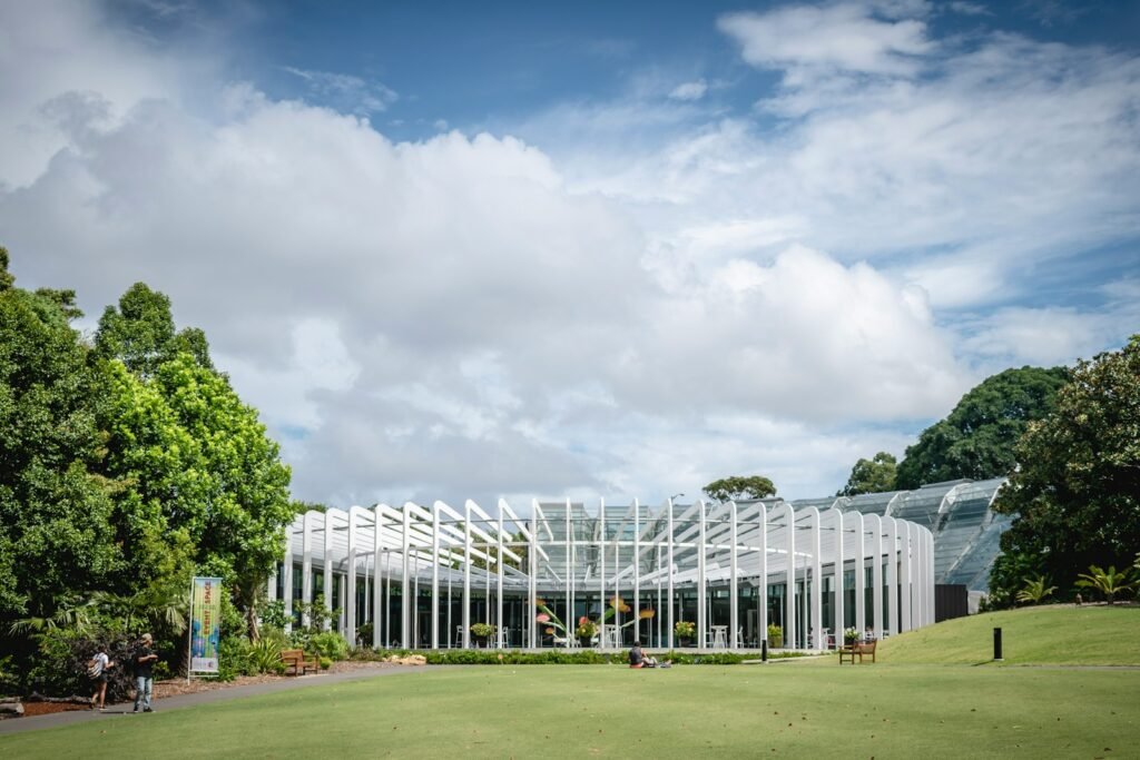 Large glass building sitting on top of a lush green field.