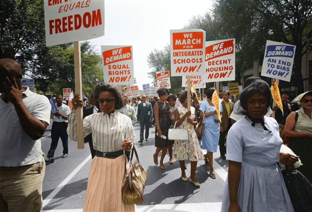 Demonstrators walk along a street holding signs demanding the right to vote and equal civil rights at the March on Washington.