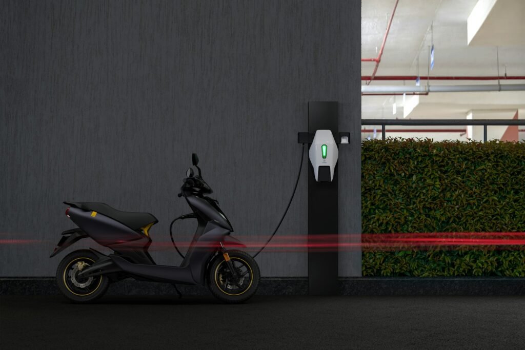 Electric motorcycle charging beside gray wall.