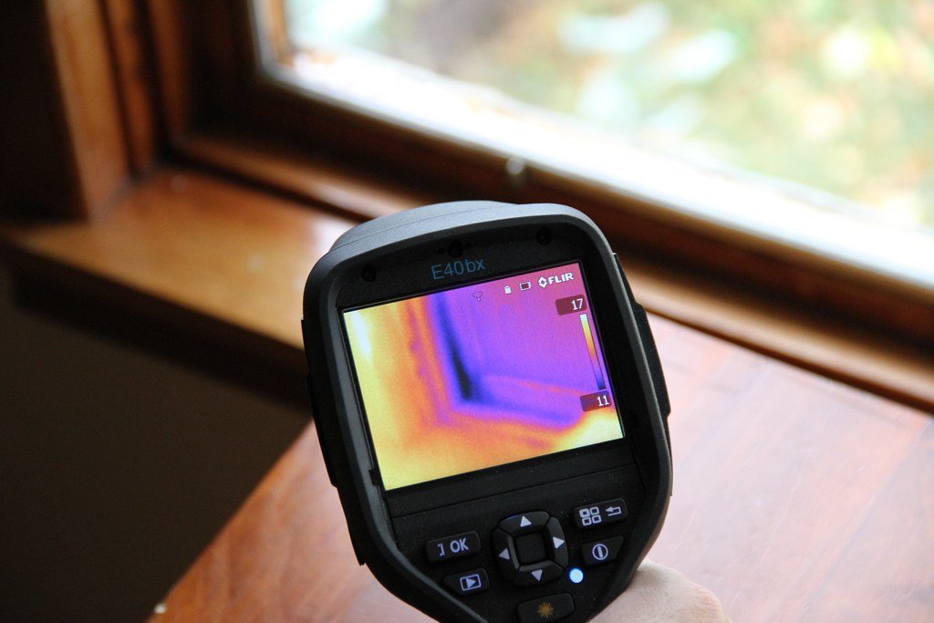 Infrared camera reveals air leakage around the windows in this older home.