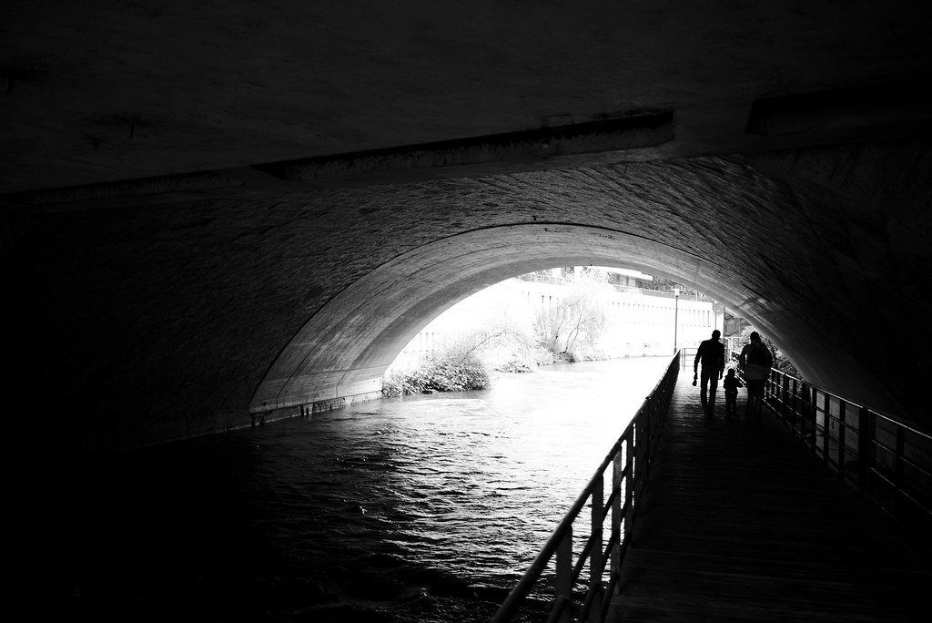 A black and white photo of a tunnel with bright light at the exit