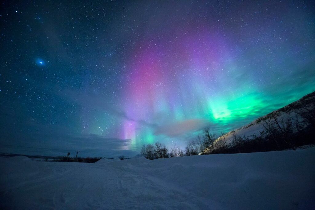northern lights over snow capped mountian.