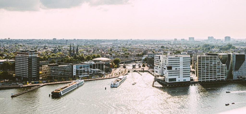 River running through a city next to tall buildings in Amsterdam.