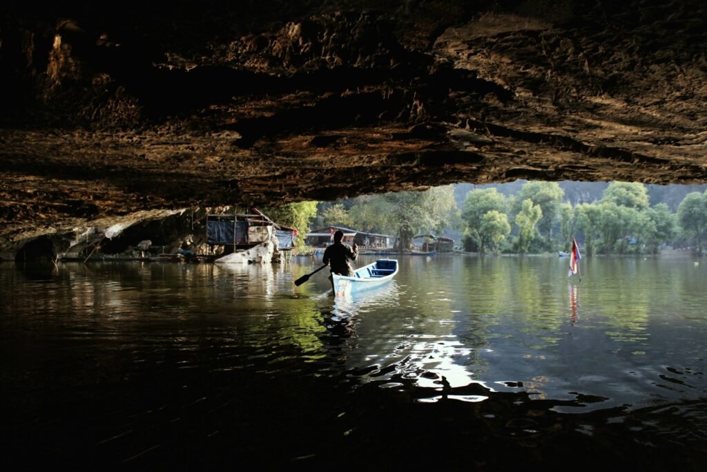 Man on a boat exiting a subterranean river.