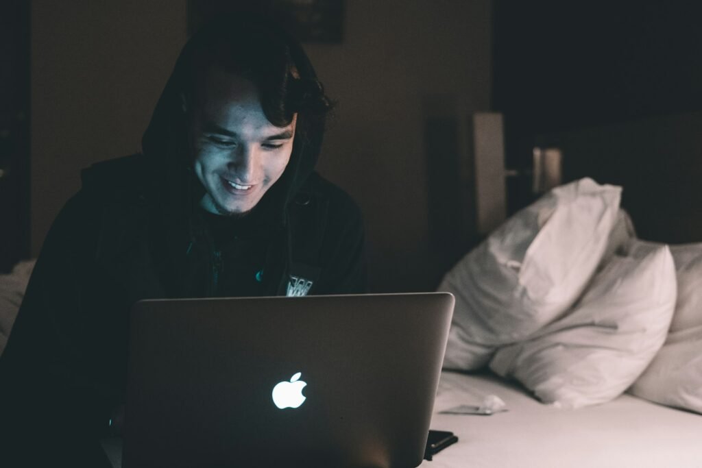 Person using MacBook in bed.