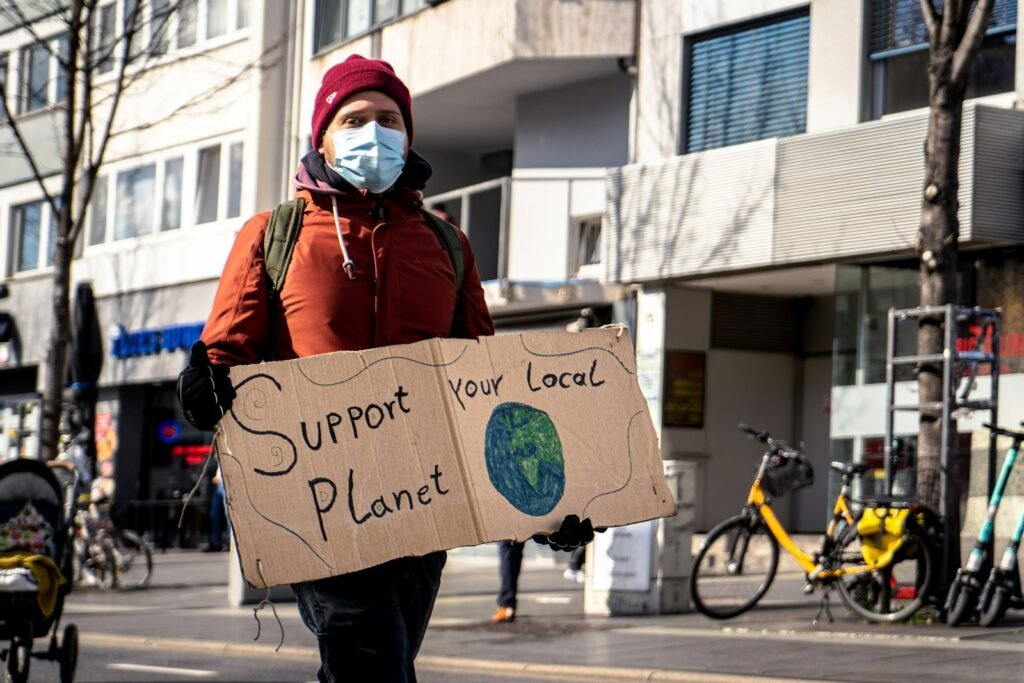 Person in red and black jacket holding a sign in a demonstration.