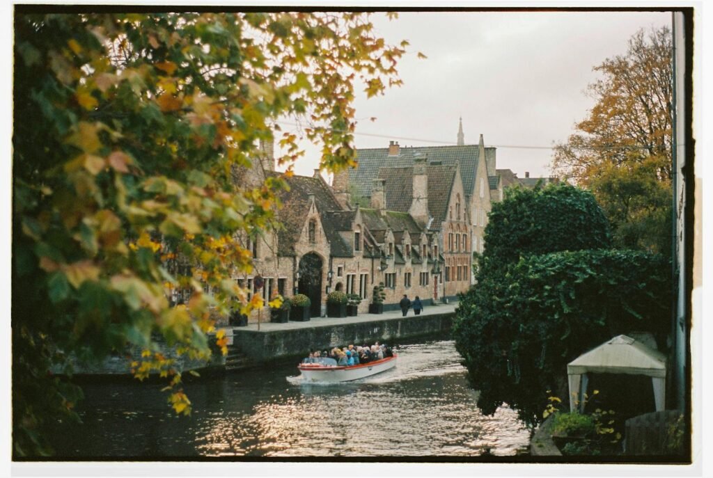 Charming autumn view of a boat tour on the scenic canals of Bruges, Belgium.