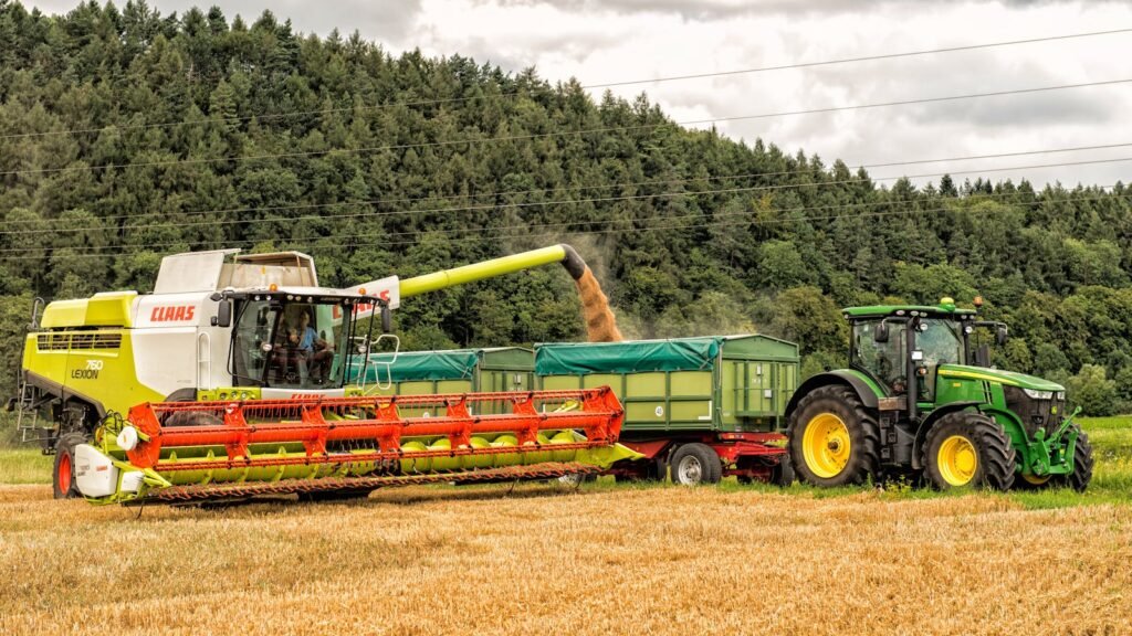 Combine harvester unloading grain into trailer in rural Höxter, Germany.