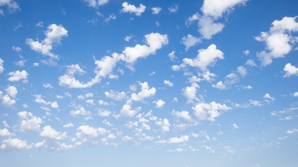 A peaceful skyscape featuring scattered cumulus clouds against a bright blue sky.
