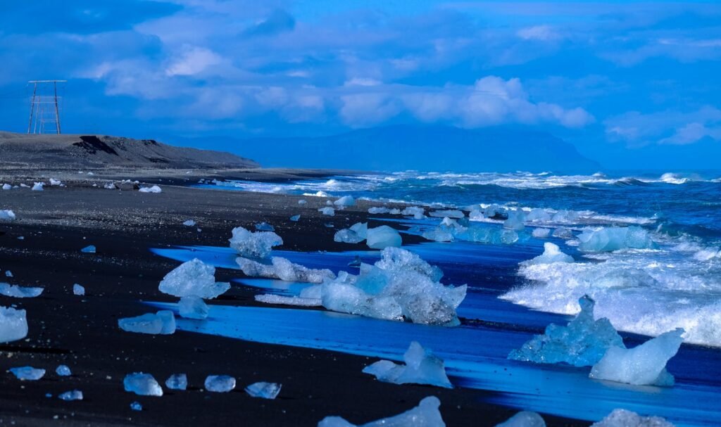 A scenic winter beach with icebergs along the shore under a moody sky, showcasing a dramatic natural landscape.