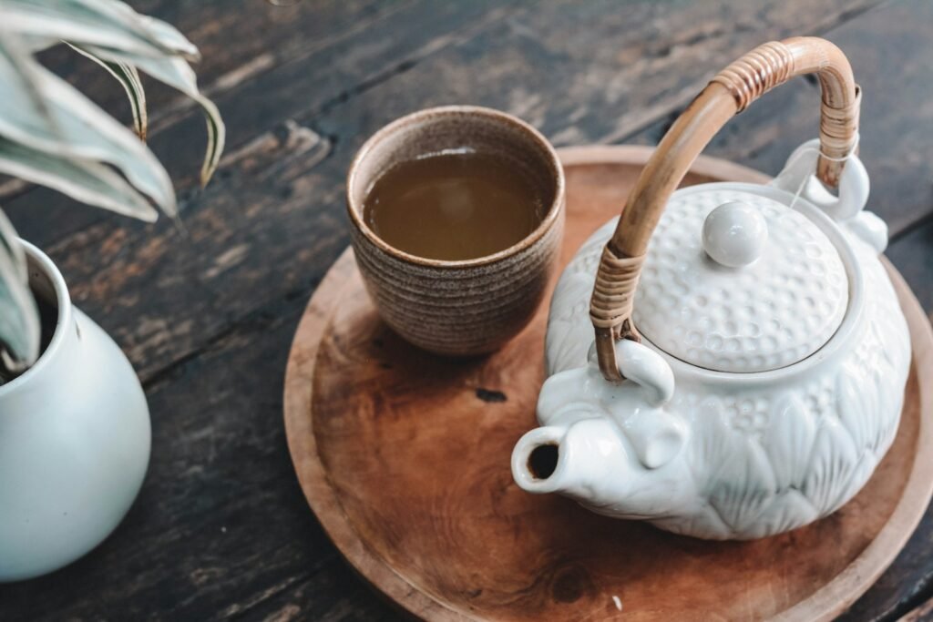 White and brown ceramic teapot on wooden tray.