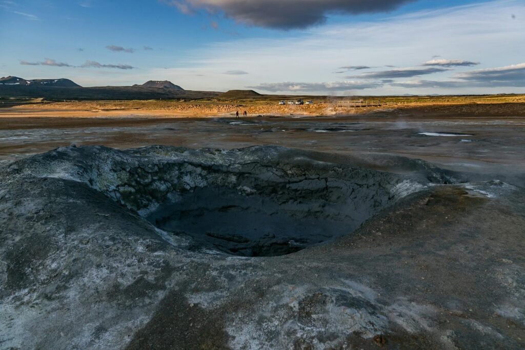 Explore the dramatic geothermal landscape with steaming vents and distant mountains.