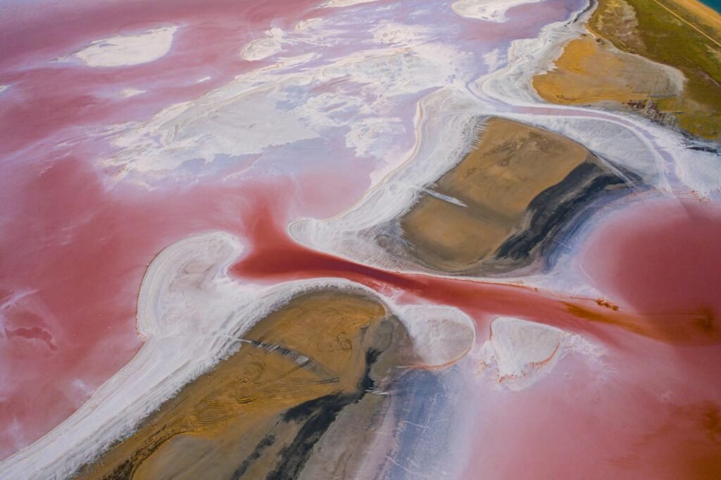 Stunning aerial view of a vibrant pink salt lake landscape with unique formations, creating a mesmerizing natural wonder.