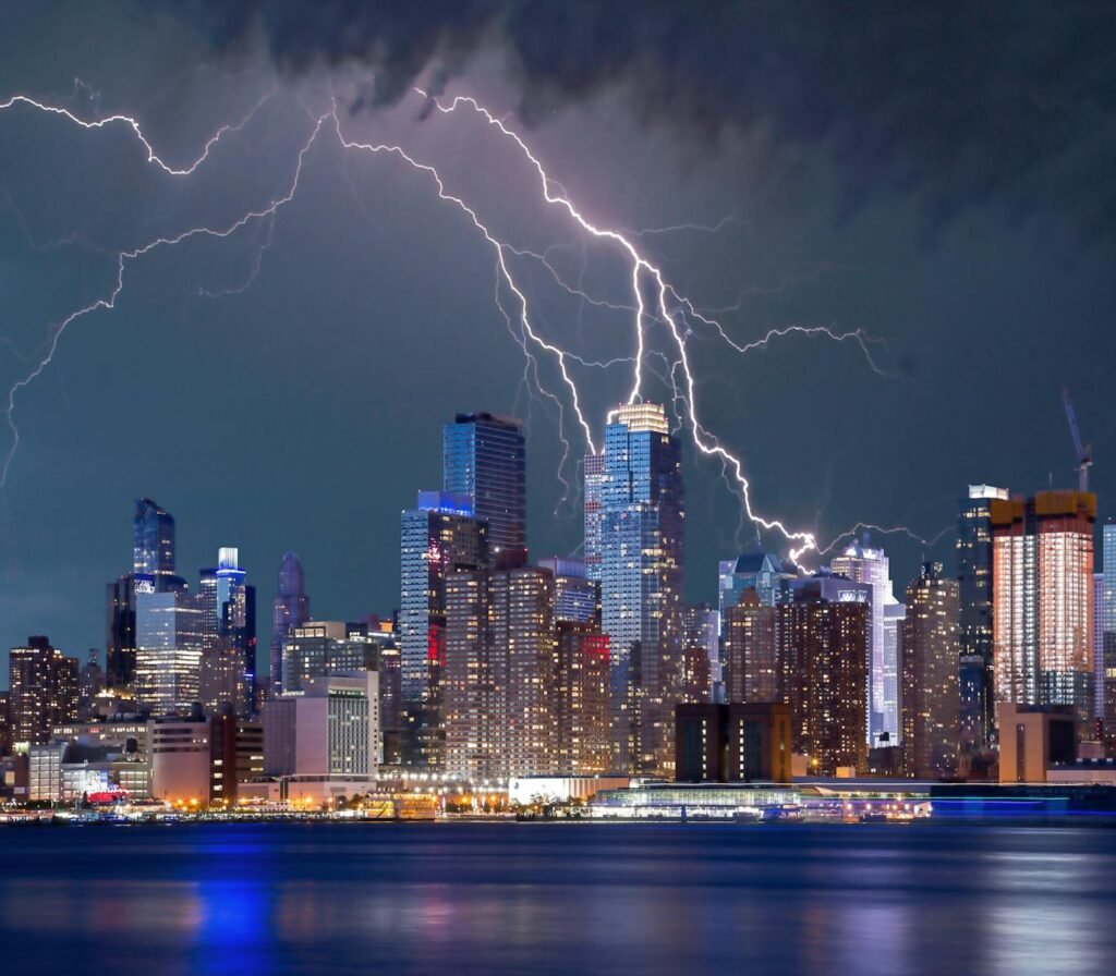 Thrilling lightning storm over a bustling urban skyline at night with stunning reflections on the waterfront.