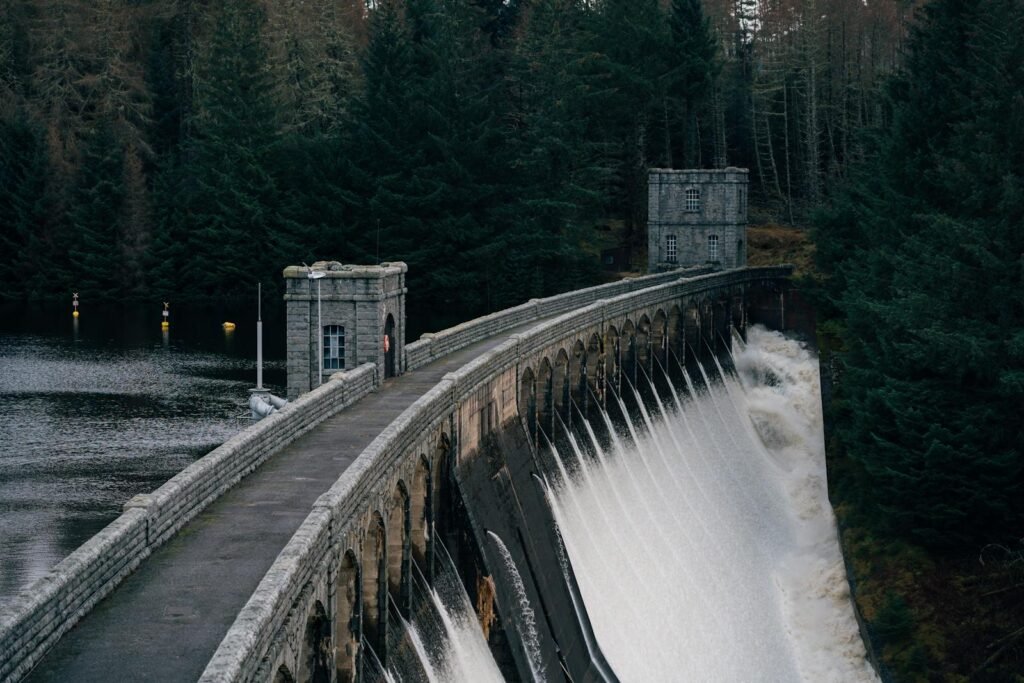 Stunning view of the Pitlochry Dam in Scotland with water cascading, surrounded by lush forests.