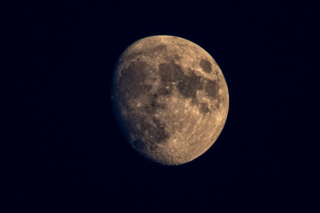 A detailed view of the waxing gibbous moon against a dark night sky, showcasing lunar craters and textures.