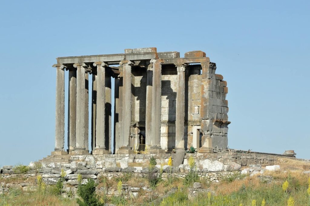 Captured in daylight, these ancient Roman temple ruins display classical architecture against a clear blue sky.