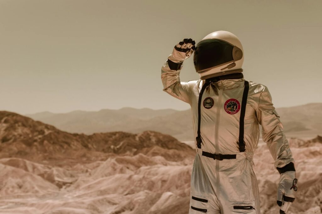An astronaut in a silver spacesuit explores a rocky desert landscape, suggesting a sci-fi theme.