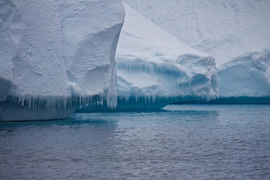 A detailed view of a massive iceberg with icicles hanging above the ocean, symbolizing the frozen beauty of nature.