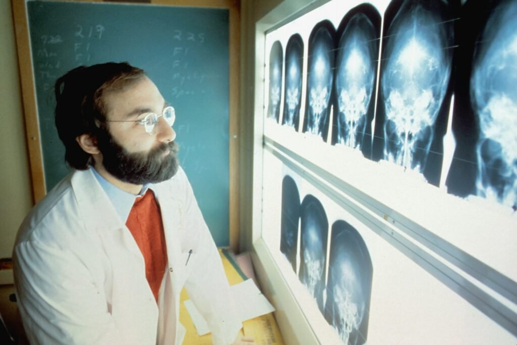 Neuroscientist in a lab coat and tie looking at an x - ray.