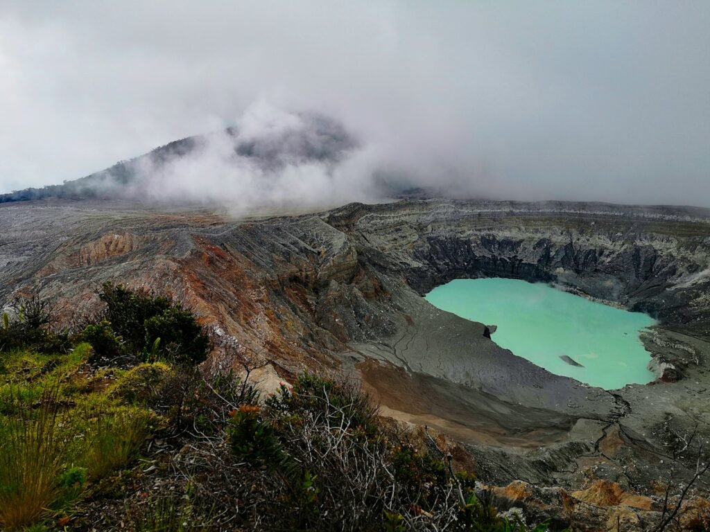 brown and green mountain beside blue sea under white clouds during daytime