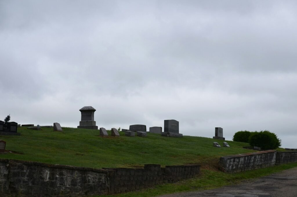 a grassy hill with a cemetery in the background