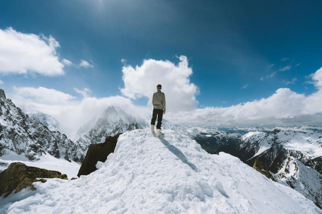 Person standing on a snow-covered peak in Chamonix-Mont-Blanc, France, showcasing a breathtaking mountain view.