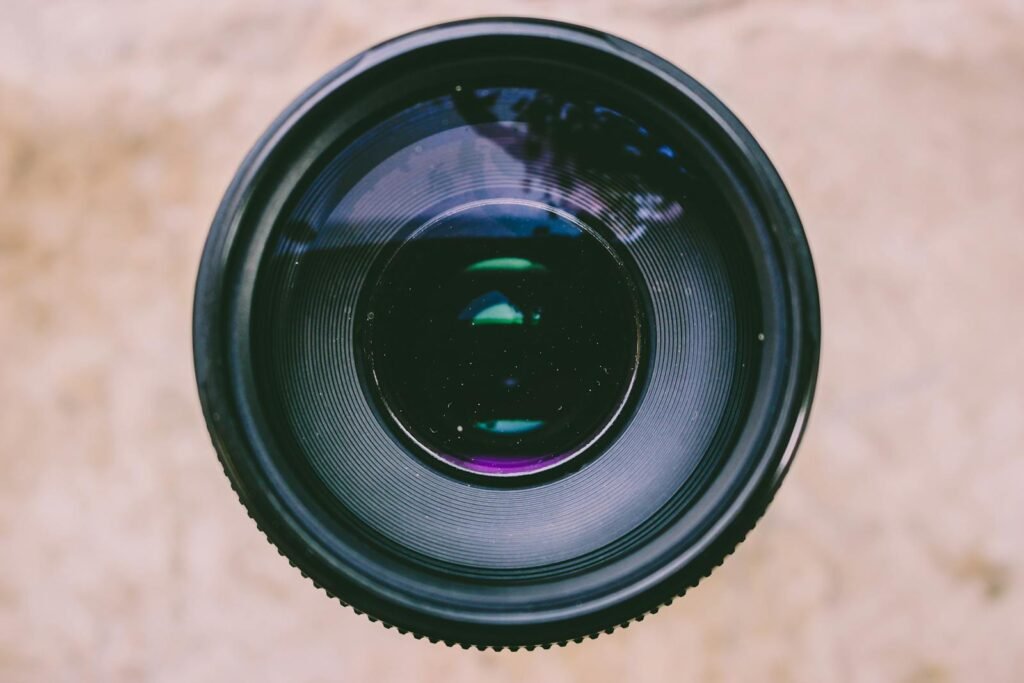 Detailed view of a camera lens capturing light and reflections, showcasing optical technology.
