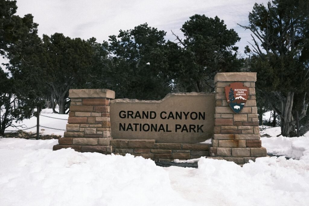 Snow-covered entrance sign to Grand Canyon National Park in winter.