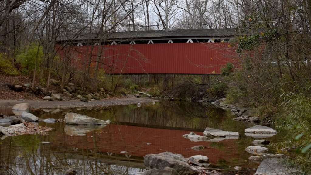 a red covered bridge over a small stream