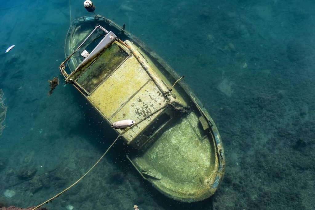 Aerial view of an abandoned boat submerged in clear blue waters off the coast of Sicily.