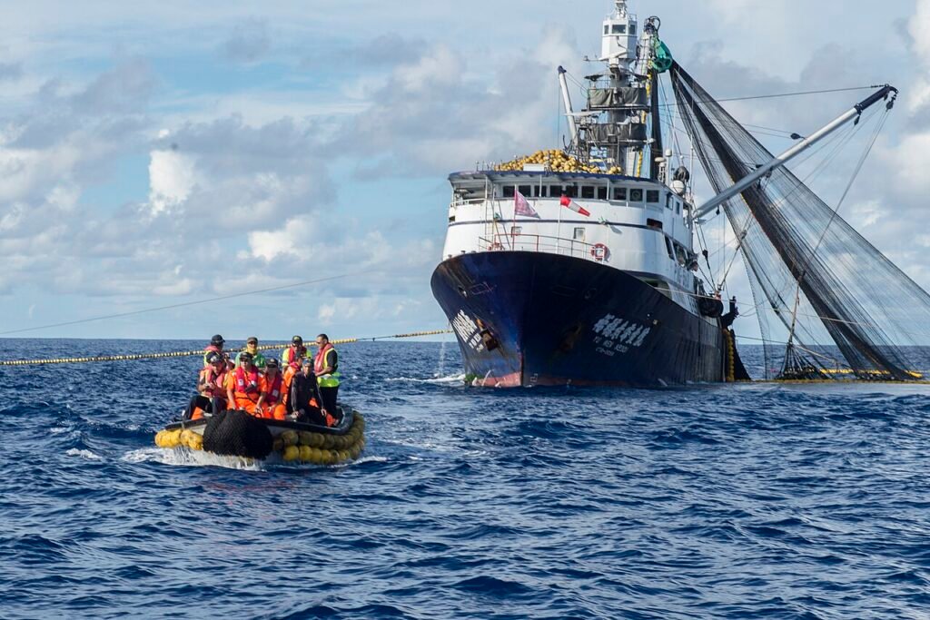 a group of men on a rubber boat in front of a fishing vessel at a close distance