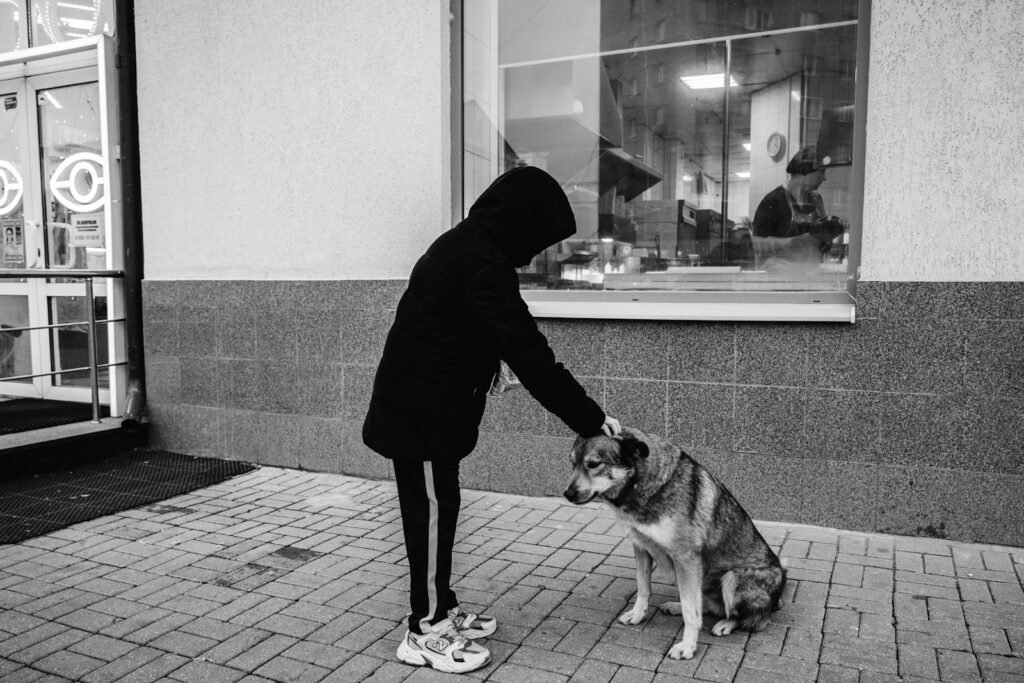 A person in a hoodie petting a dog