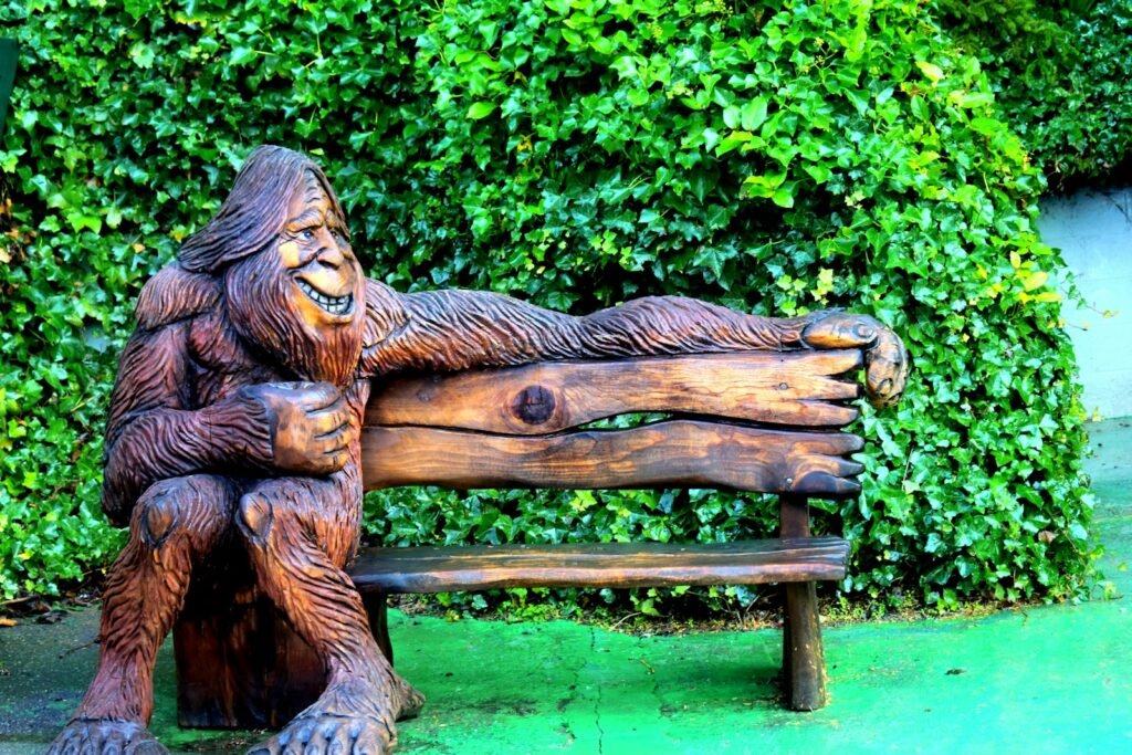 A statue of a gorilla sitting on top of a wooden bench