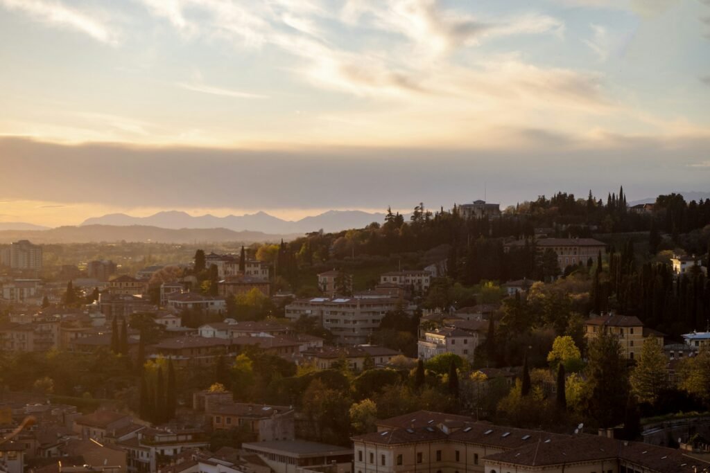 the sun is setting over a city with mountains in the background